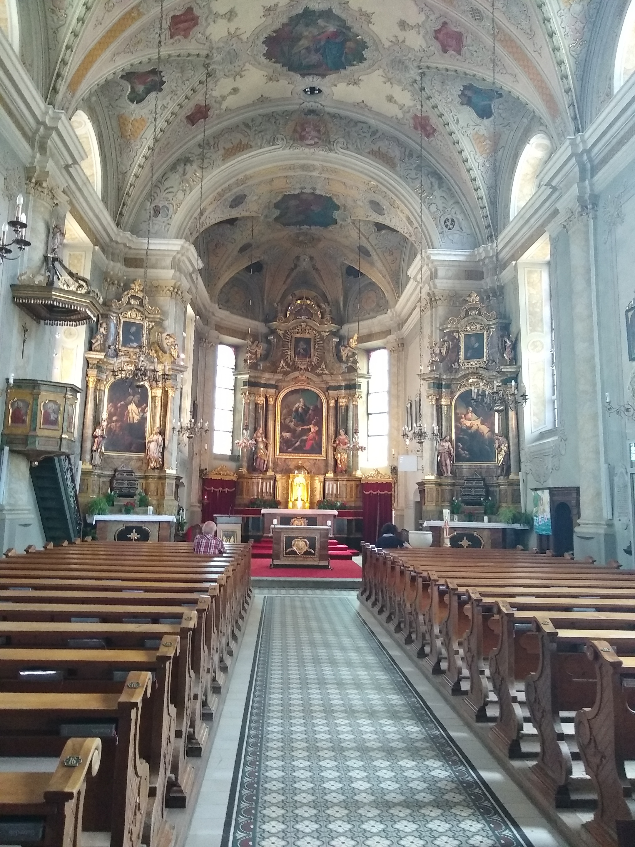 Blick ins barocke Kircheninnere vom Eingang aus, rechts und links dunkle Holzkirchenbände