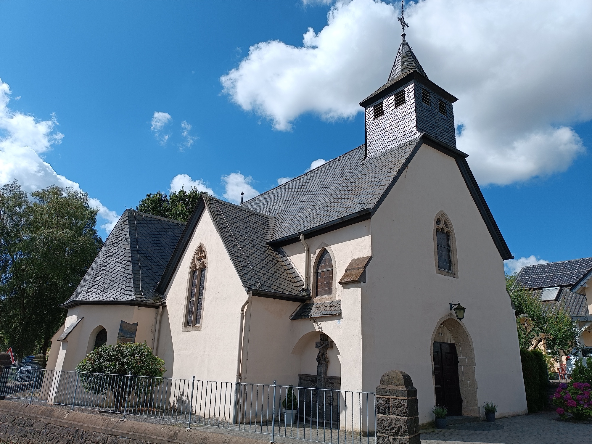 Man sieht den Kircheneingang von der Kirchstraße aus, die Kirche ist gelb verputzt