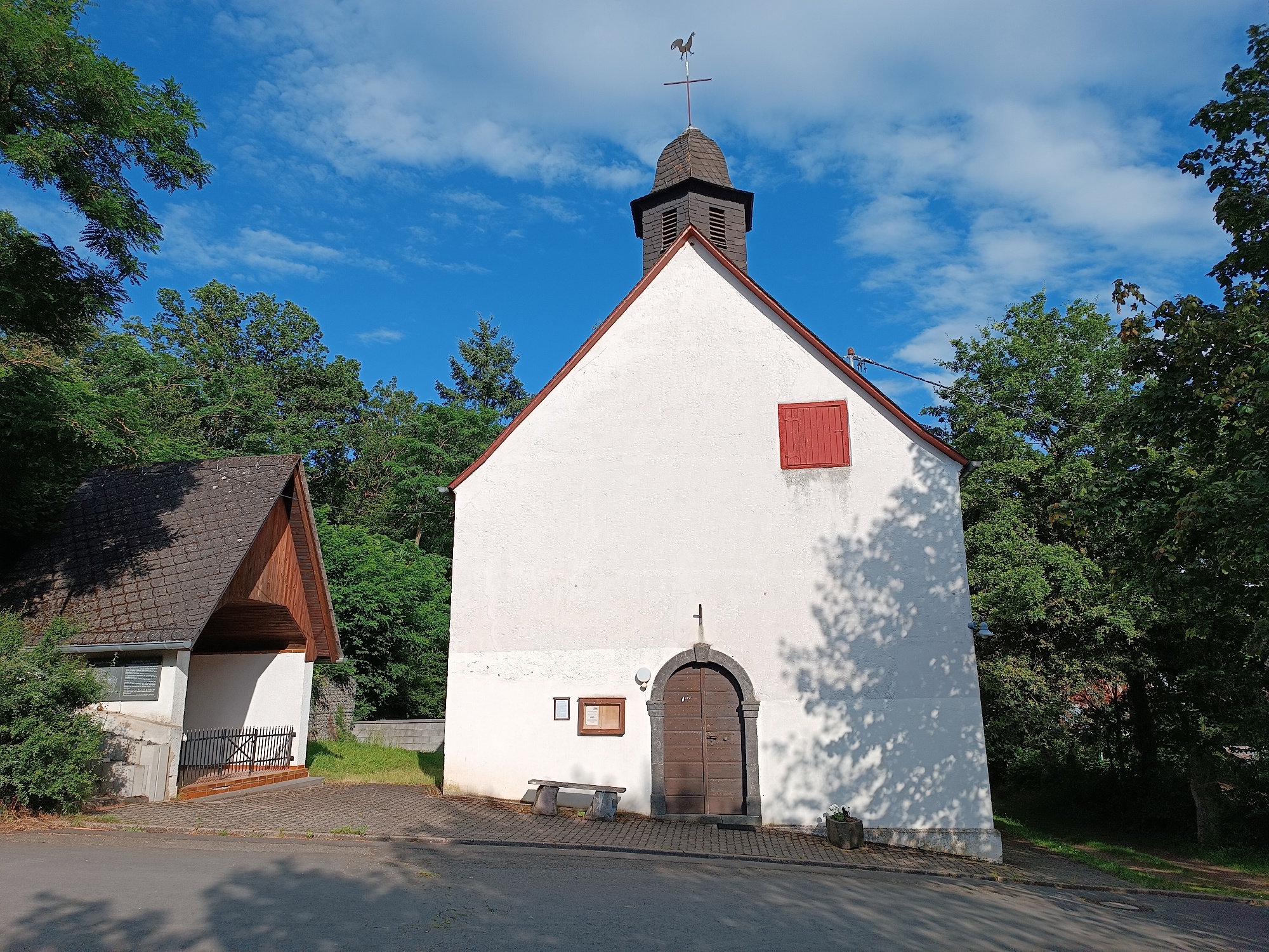 Blick auf den Kircheneingang mit kleiner Kapelle links