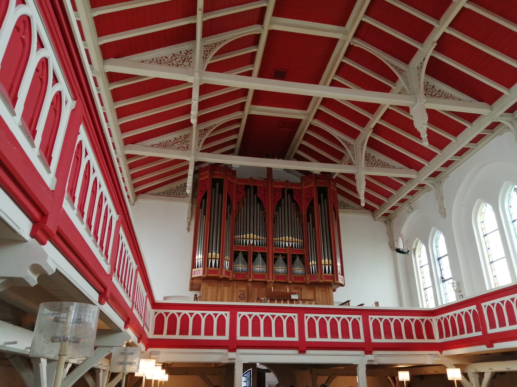 Man sieht die Decke der Kirche, die mit rotem Holz und weißen Balken ausgekleidet ist