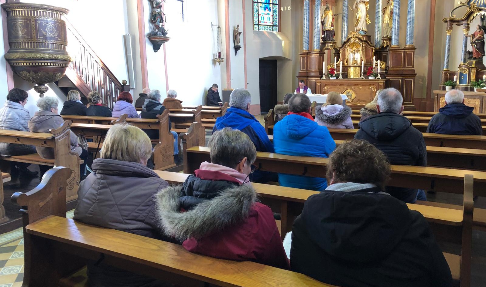 Man sieht Gottesdienstteilnehmer*innen in der Kirche in Pillig auf den Bänken sitzen