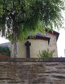 Man sieht die Aussenansicht der Kirche mit Kreuz, vom Friedhof aus